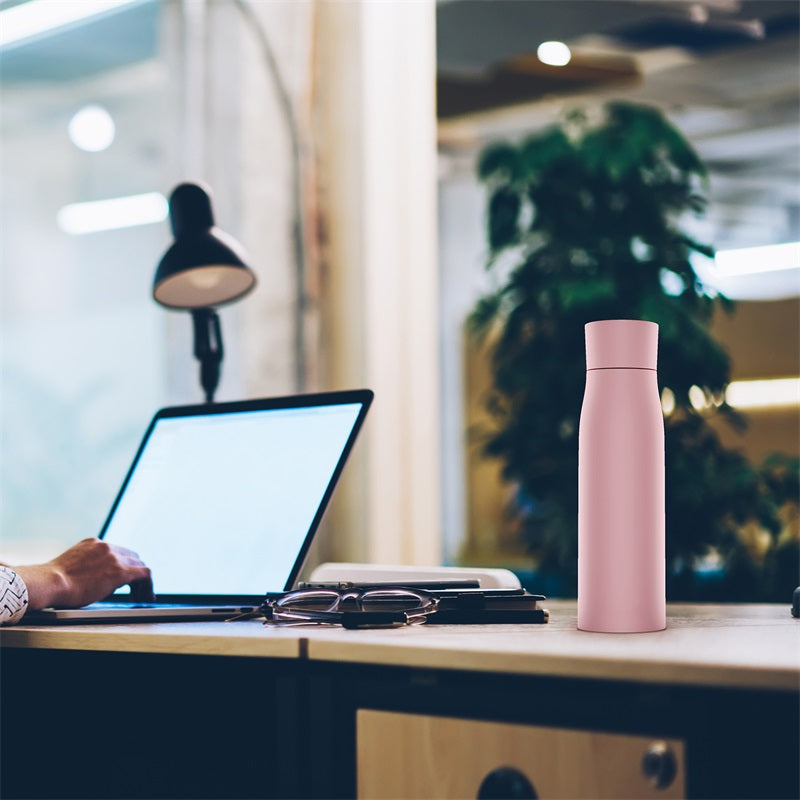 Pink insulated thermal water bottle on an office desk, smart temperature display