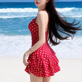 Red polka-dot one-piece swimsuit with halter neckline and layered ruffle skirt