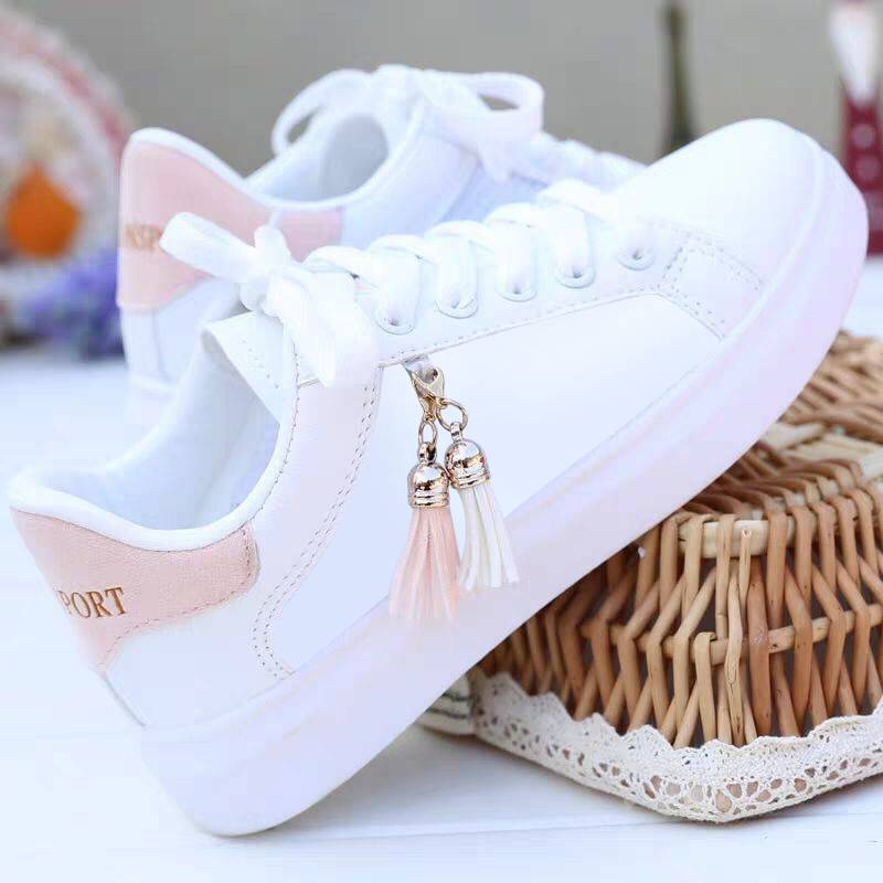 White low-top sneakers with pink side panel and tassel charm, lace-up.