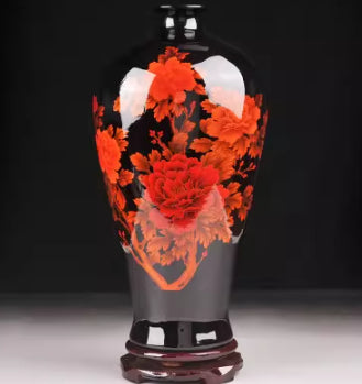 Ceramic vase with dense orange-red floral design and glossy dark rim, on pedestal