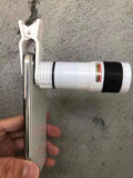 White clip-on telescope camera lens with metal mount and black grip, handheld phone